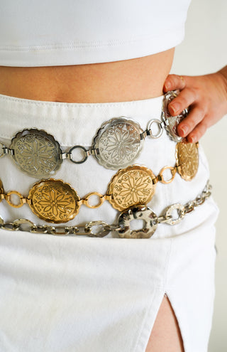 A woman pair a concho belt with an orange dress for a stylish statement.