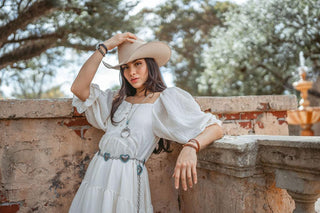 A woman pair a concho belt with an orange dress for a stylish statement.